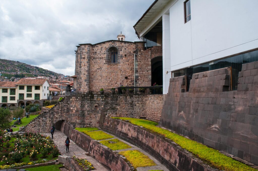 View of the historic Coricancha temple in Cusco, featuring Inca stonework and gardens.